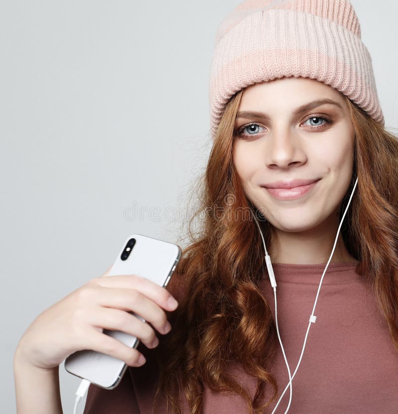 Mode de vie et concept de personnes : jeune femme dans des écouteurs avec le smartphone écoutant la musique photographie stock libre de droits Mode de vie et concept de personnes : jeune femme dans des écouteurs avec le smartphone écoutant la musique photographie stock libre de droits