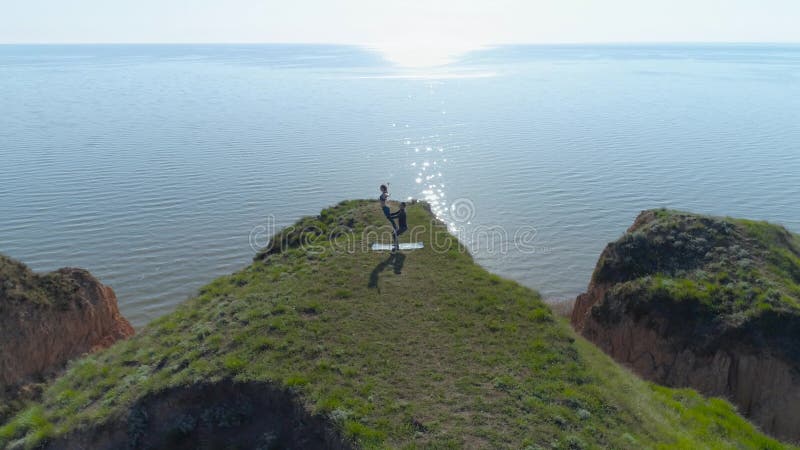 Mode de vie sain, paire de yogi de sports faisant la formation d'acroyoga de flexibilité sur la falaise près de l'océan, vue de b