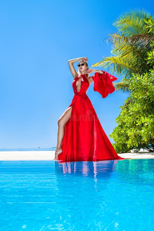 Mode De Luxe. Mannequin Élégant. Modèle Féminin Élégant En Robe Longue  Rouge Sur La Plage Des Maldives. Élégance. Femme Chic En Robe Rouge  Incroyable Près De La Piscine. Couture. Vogue. Banque D'Images