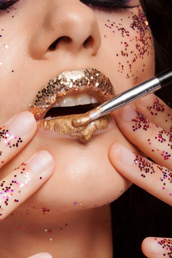 Mode-Modell mit den perfekten Lippen bedeckt mit goldenem Lippenstift und Funkeln lizenzfreie stockbilder Mode-Modell mit den perfekten Lippen bedeckt mit goldenem Lippenstift und Funkeln lizenzfreie stockbilder