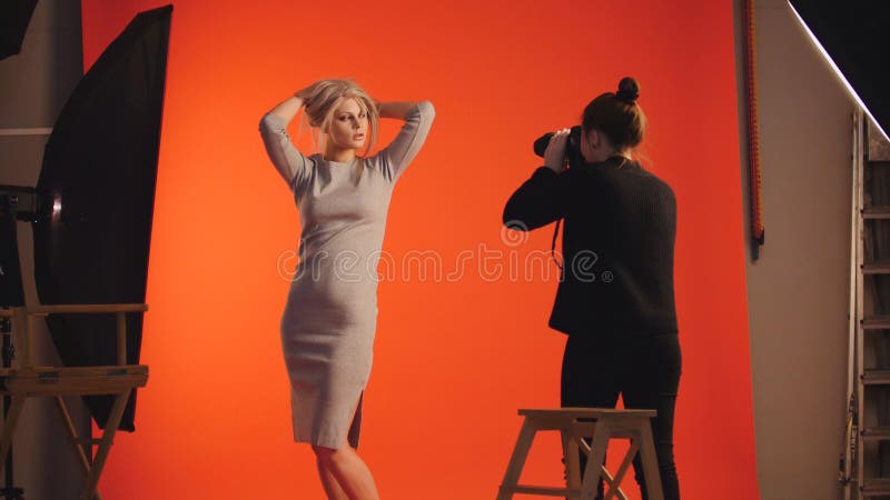 Mode à l'arrière plan : modèle de fille et photographe blonds - séance photo dans le studio photographie stock Mode à l'arrière plan : modèle de fille et photographe blonds - séance photo dans le studio photographie stock