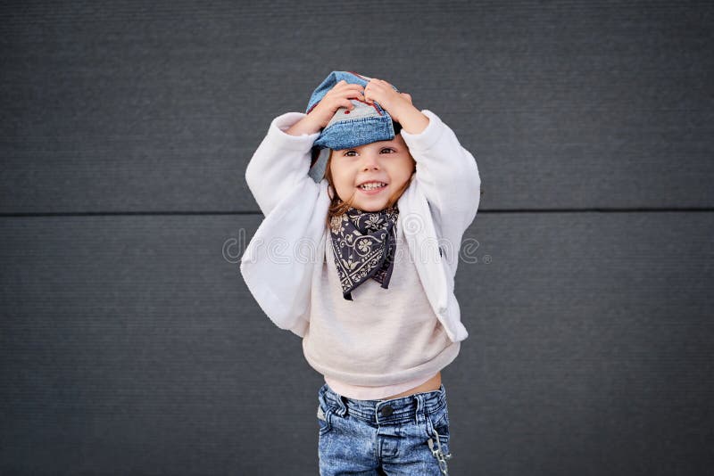 Cute baby in blue jeans, white t-shirt and denim baseball cap sits isolated  on white background Stock Photo