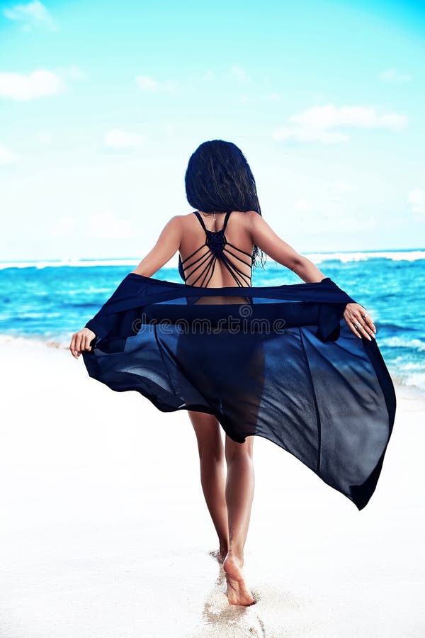 Portrait of beautiful caucasian sunbathed woman model with dark long in  swimsuit posing on summer beach