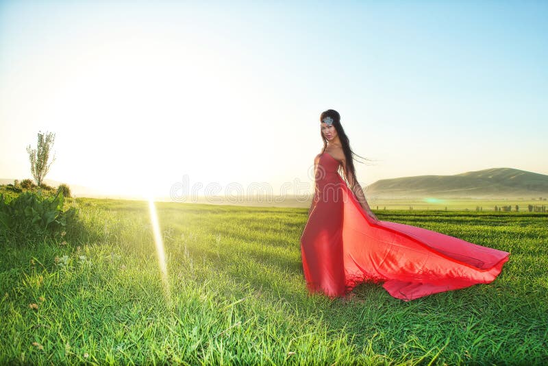 Model in het rode kleding stellen op het gebied bij zonsondergang stock fotografie Model in het rode kleding stellen op het gebied bij zonsondergang stock fotografie