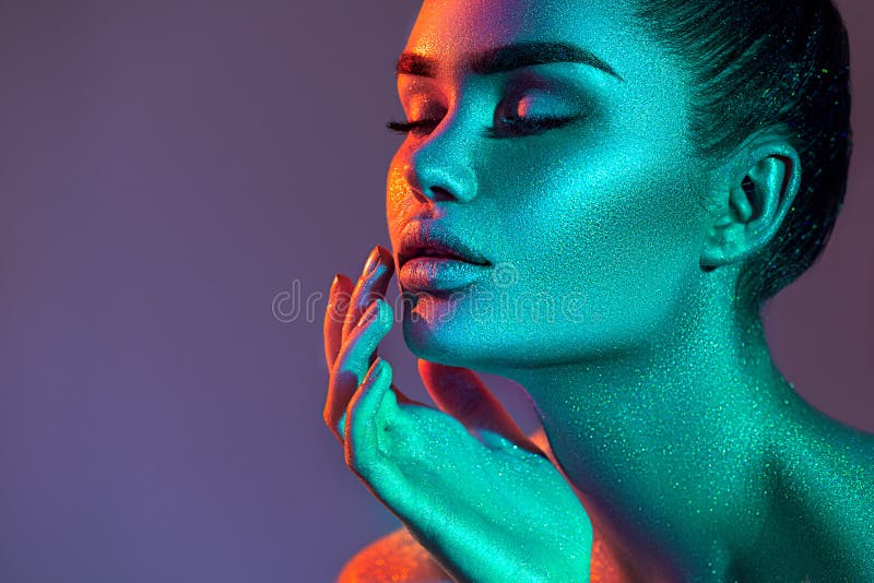 Model woman in colorful bright sparkles and neon lights posing in studio, high fashion portrait of beautiful sexy girl, trendy mak