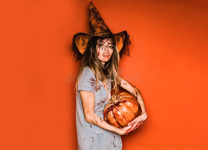 Modelka z krwawymi rękami i krwią na twarzy. szczęśliwa młoda kobieta kostium halloween z kapeluszem stojącym na czerwonym tle zdjęcie stock