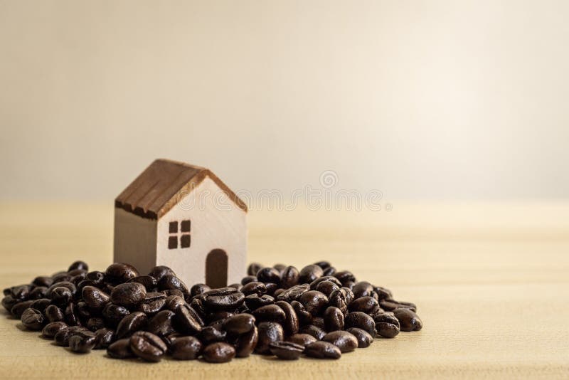 Model of a house on a pile of coffee beans brown background. Model of a house on a pile of coffee beans brown background.