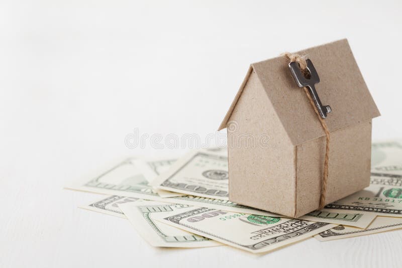 Model of cardboard house with key and dollar bills. House building, loan, real estate, cost of housing or buying a new home concept. Model of cardboard house with key and dollar bills. House building, loan, real estate, cost of housing or buying a new home concept.