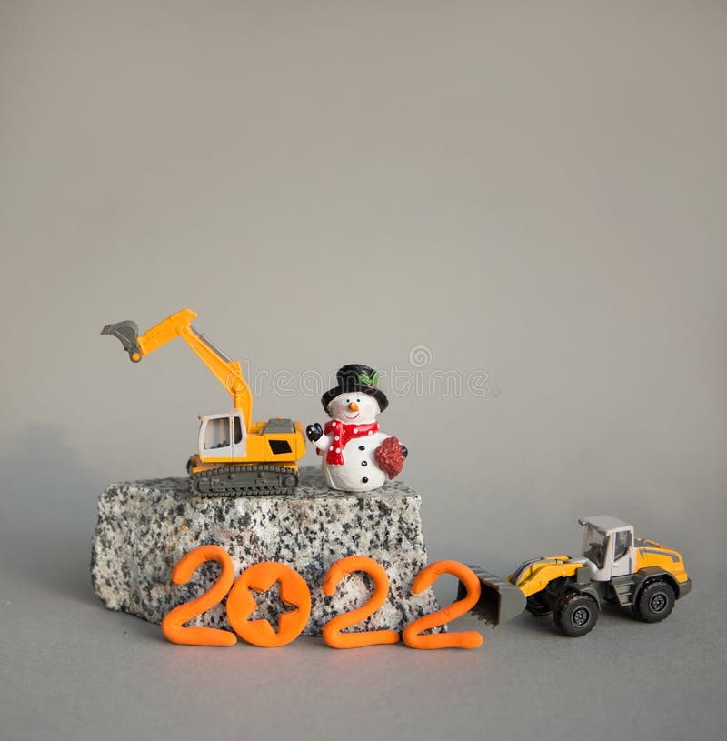 Modeller av leksaksapelsingrävare och lastare står på en granitsovenirsnowman 2022-nummer arkivfoton