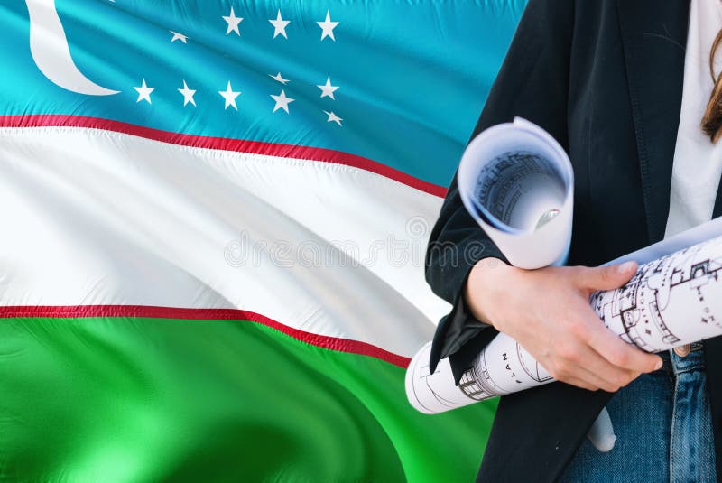 Modello della tenuta della donna dell'architetto dell'Uzbeco contro il fondo d'ondeggiamento della bandiera dell'Uzbekistan Conce immagine stock libera da diritti Modello della tenuta della donna dell'architetto dell'Uzbeco contro il fondo d'ondeggiamento della bandiera dell'Uzbekistan Conce immagine stock libera da diritti