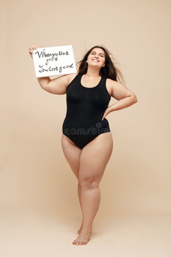 Modello di dimensione maggiore. donna grassa con tuta nera ritratto a piena lunghezza. carta per uso femminile con le parole. immagini stock libere da diritti