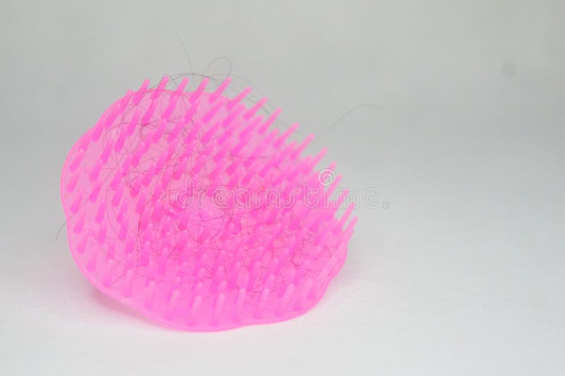 Modello esclusivo di pettine rosa rotondo in plastica all'interno del quale sono fissati i capelli. immagini stock