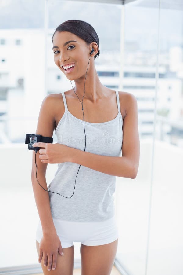 Modello grazioso sorridente nella canzone cambiante degli abiti sportivi sul suo mp3 immagini stock Modello grazioso sorridente nella canzone cambiante degli abiti sportivi sul suo mp3 immagini stock
