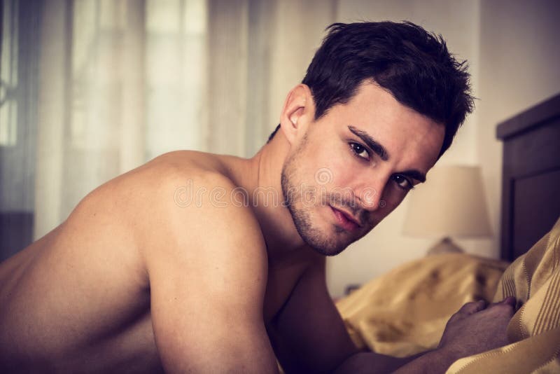 Modello maschio sexy senza camicia che si trova da solo sul suo letto fotografia stock libera da diritti Modello maschio sexy senza camicia che si trova da solo sul suo letto fotografia stock libera da diritti