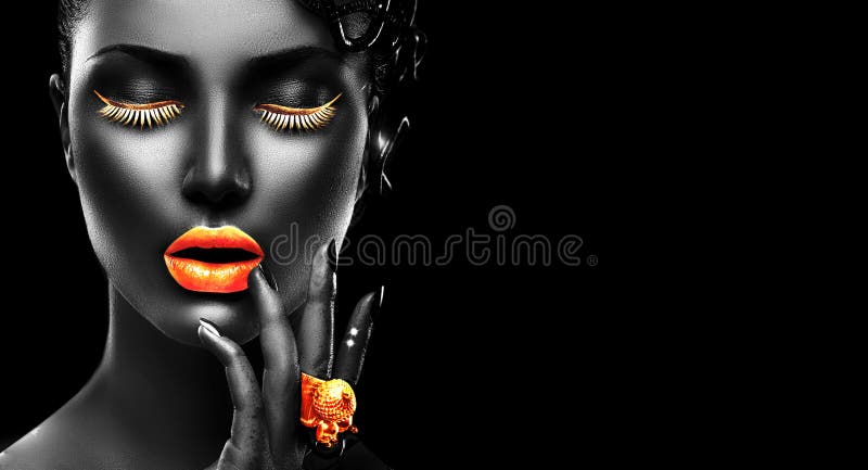 Modelo de moda con la piel negra, los labios de oro, las pestañas y la joyería - anillo de oro a mano En fondo negro