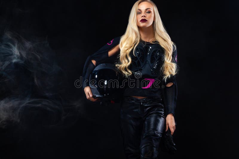 Modelo de moda DJ y motorista en auriculares, chaqueta de cuero negra, pantalones de cuero, mujer rubia bonita elegante en noche imagenes de archivo Modelo de moda DJ y motorista en auriculares, chaqueta de cuero negra, pantalones de cuero, mujer rubia bonita elegante en noche imagenes de archivo