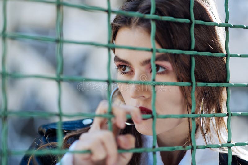 Modelo elegante sério da foto que levanta perto da cerca no estádio fotografia de stock Modelo elegante sério da foto que levanta perto da cerca no estádio fotografia de stock