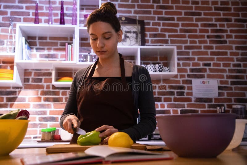 Modelo femenino atractivo que corta verduras en la cocina fotografía de archivo libre de regalías Modelo femenino atractivo que corta verduras en la cocina fotografía de archivo libre de regalías