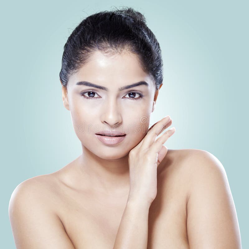 Young female model with clean skin after skincare, looking at the camera in the studio on blue background. Young female model with clean skin after skincare, looking at the camera in the studio on blue background