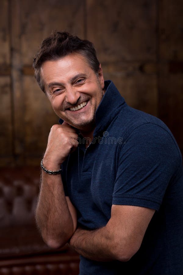 Modelo masculino emocional que sorri e que põe sua mão à cara Retrato do homem feliz que toca em seu queixo ao sorrir imagens de stock Modelo masculino emocional que sorri e que põe sua mão à cara Retrato do homem feliz que toca em seu queixo ao sorrir imagens de stock