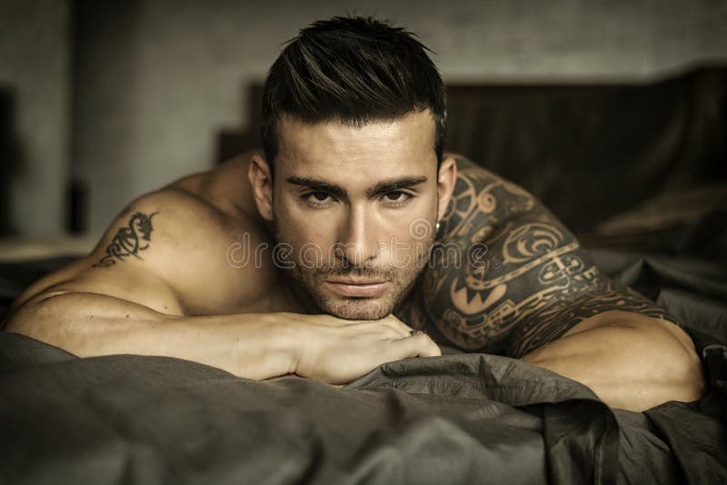 Modelo masculino 'sexy' descamisado que encontra-se apenas em sua cama