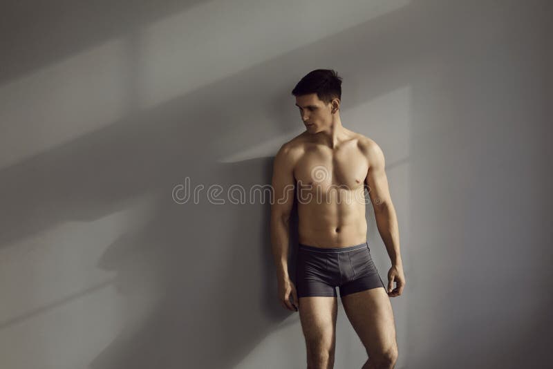 Modelo Masculino Sin Camisa Muscular En Ropa Interior Posando En Posición Sensual Contra Fondo De Pared Gris. Imagen de archivo - Imagen aptitud, muchacho: 236649887
