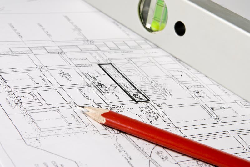 Spread out construction blueprints with a red pencil and a spirit level atop. Spread out construction blueprints with a red pencil and a spirit level atop