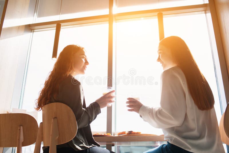 Modelos femininos sentam-se e falam em café. mulheres jovens tomando café durante o almoço