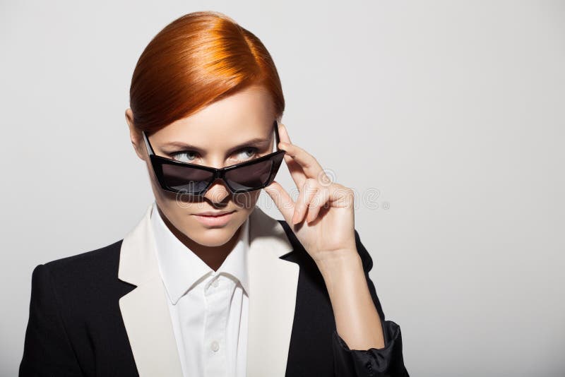 Fashion portrait of serious woman dressed as a secret agent or spy. Gray background. Fashion portrait of serious woman dressed as a secret agent or spy. Gray background.