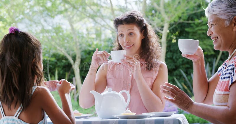 Moder, dotter och farmor som har te i gräsmattan 4K 4k