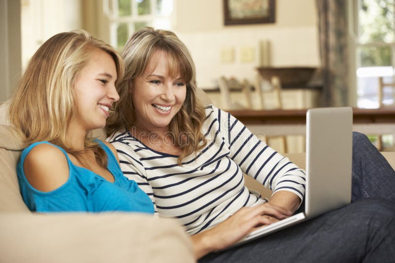 Moder med sammanträde för tonårs- dotter på Sofa At Home Using Laptop royaltyfri foto Moder med sammanträde för tonårs- dotter på Sofa At Home Using Laptop royaltyfri foto