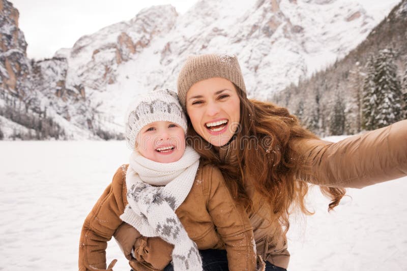 Moder och barn som tar selfie bland snö-korkade berg royaltyfri bild Moder och barn som tar selfie bland snö-korkade berg royaltyfri bild