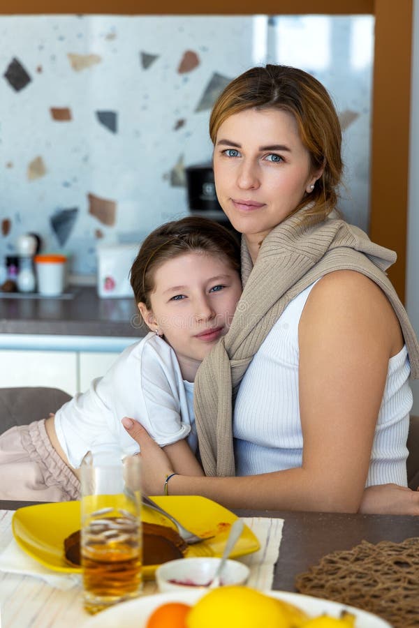 Moder och dotter kramar under frukost. Loving-mamman välkomnar hennes dotter vid frukostbordet och delar ett lugn och royaltyfri bild