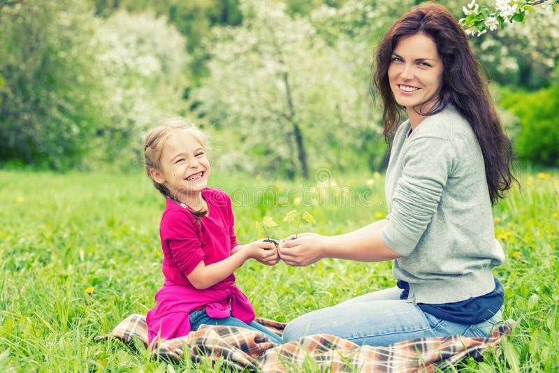 Moder och dotter som rymmer den lilla gröna växten i händer arkivfoto Moder och dotter som rymmer den lilla gröna växten i händer arkivfoto