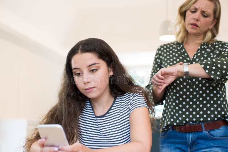 Moder som argumenterar med den tonårs- dottern över bruk av mobiltelefonen arkivbild Moder som argumenterar med den tonårs- dottern över bruk av mobiltelefonen arkivbild