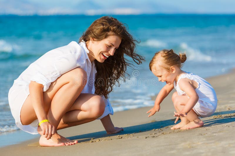 Moder som leker med dottern på stranden arkivbild