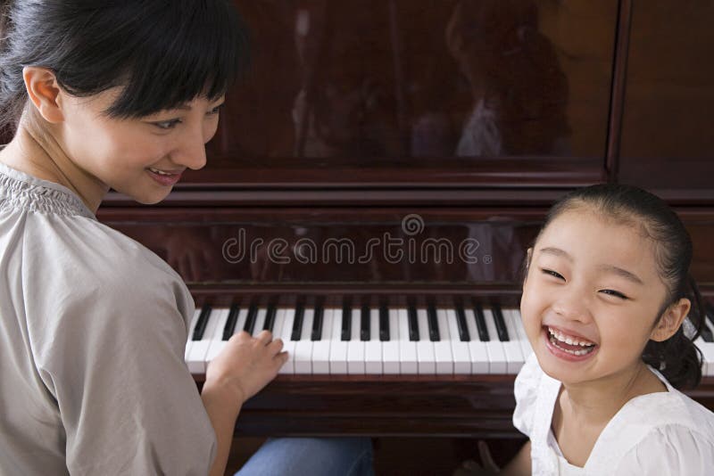 Moder som spelar pianot för hennes dotter arkivfoto