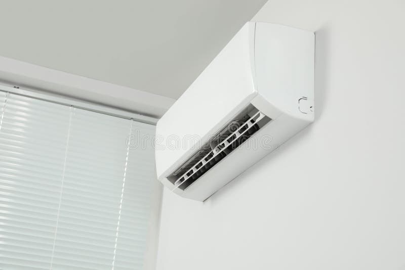 Modern Air Conditioner on White Wall Indoors, Low Angle View Stock