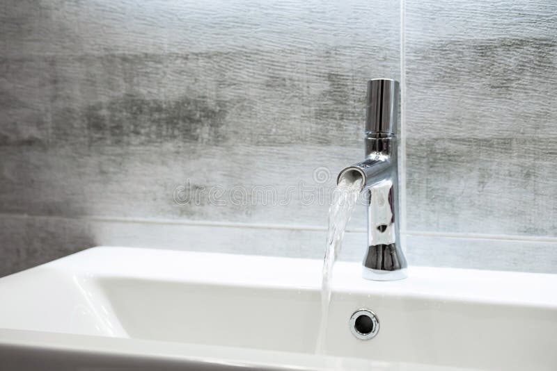 Modern Bathroom Faucet. Flowing Water from Water Tap, Copy Space Stock