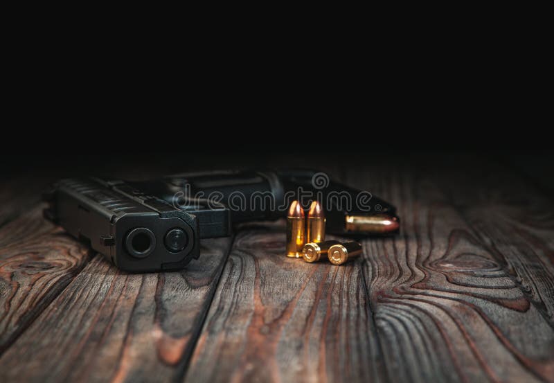 Modern black gun and ammunition  on a wooden background. Pistol. Weapons for sport and self-defense lie on the table stock photo