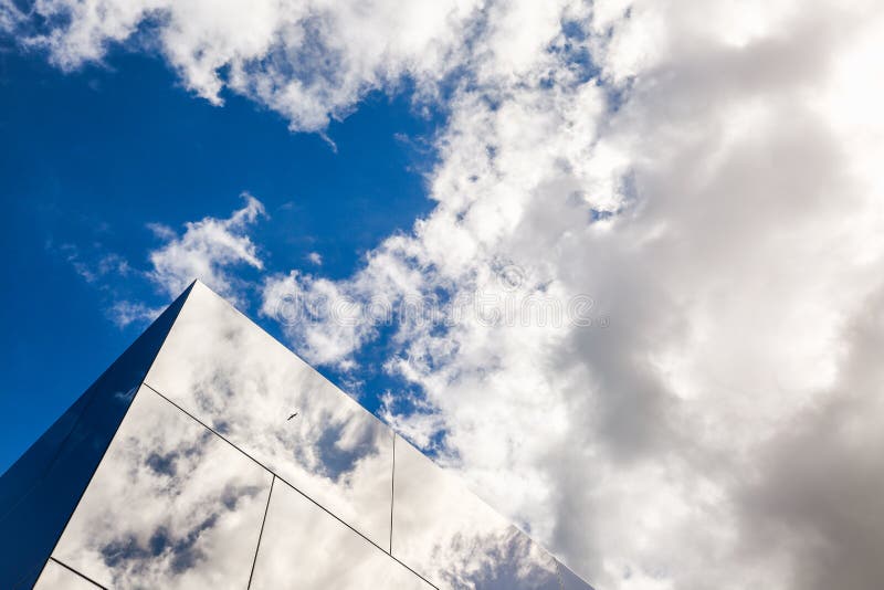 Modern building exterior design, glass facade. Reflection of bird and cloudy sky in glass. Urban background. Skyline architecture.