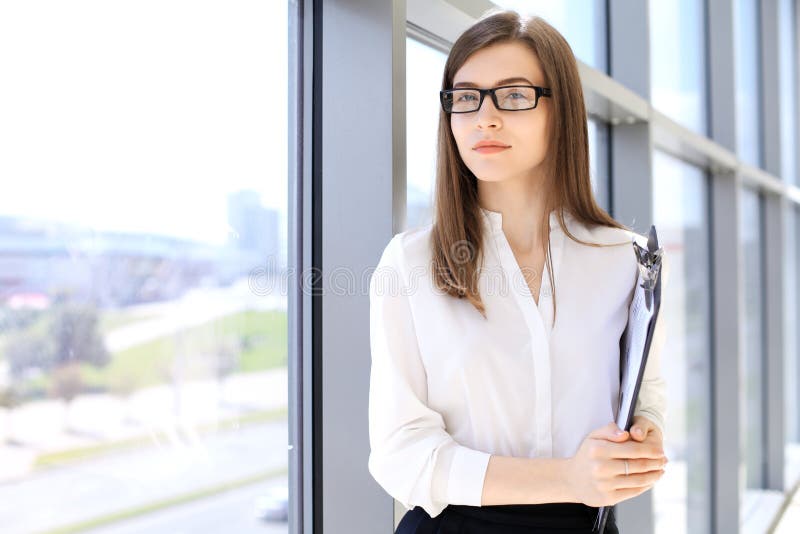 Modern business woman standing and keeping a clipboard in the office