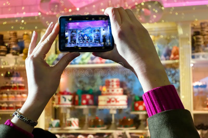 Woman taking pictures of a Fifth Avenue shop window festively decorated for the Christmas season. The store front windows of large, famous department stores (Macys, Lord & Taylor, Saks, Bloomingdales) become tourist attractrions in December, drawing huge crowds. Woman taking pictures of a Fifth Avenue shop window festively decorated for the Christmas season. The store front windows of large, famous department stores (Macys, Lord & Taylor, Saks, Bloomingdales) become tourist attractrions in December, drawing huge crowds.