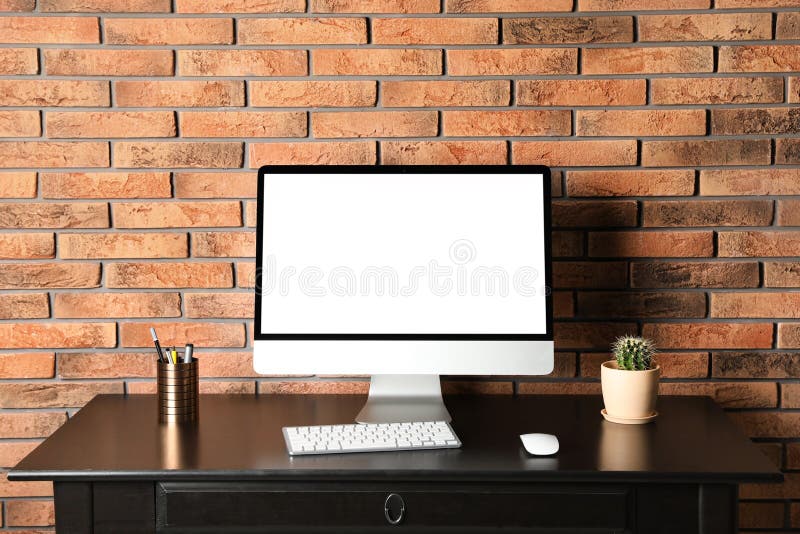 Modern computer monitor on desk brick wall, mock up with space for text royalty free stock photography