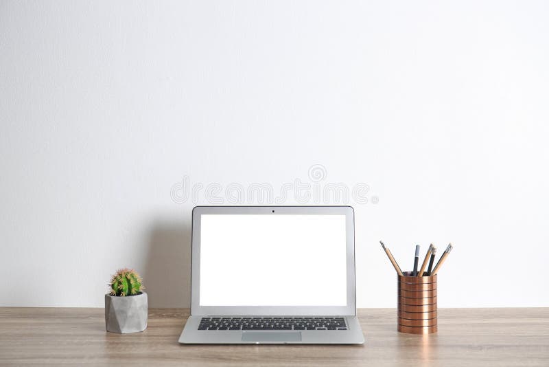 Modern computer monitor on table against white wall. Mock up with space for text