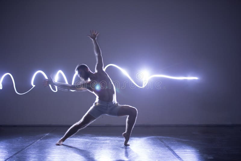 Modern Dance performer dancing with a neon blue light while making gracious moves and spectacular body art expressions royalty free stock images Modern Dance performer dancing with a neon blue light while making gracious moves and spectacular body art expressions royalty free stock images