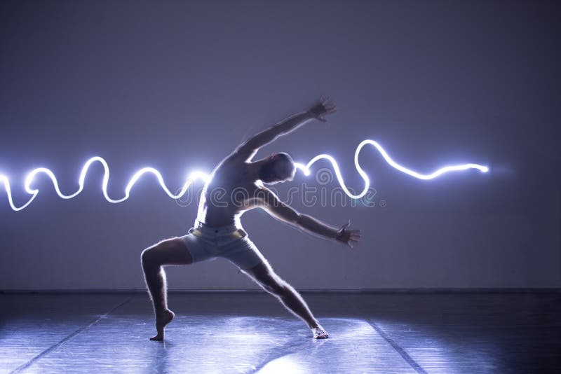 Modern Dance performer dancing with a neon blue light while making gracious moves and spectacular body art expressions stock image Modern Dance performer dancing with a neon blue light while making gracious moves and spectacular body art expressions stock image
