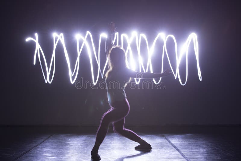 Modern Dance performer dancing with a neon blue light while making gracious moves and spectacular body art expressions stock photos Modern Dance performer dancing with a neon blue light while making gracious moves and spectacular body art expressions stock photos