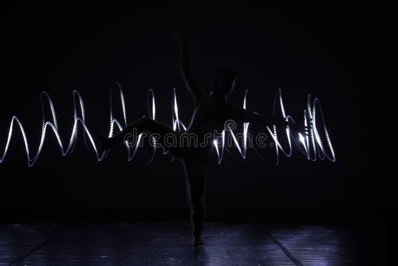 Modern Dance performer dancing with a neon blue light while making gracious moves and spectacular body art expressions royalty free stock image Modern Dance performer dancing with a neon blue light while making gracious moves and spectacular body art expressions royalty free stock image