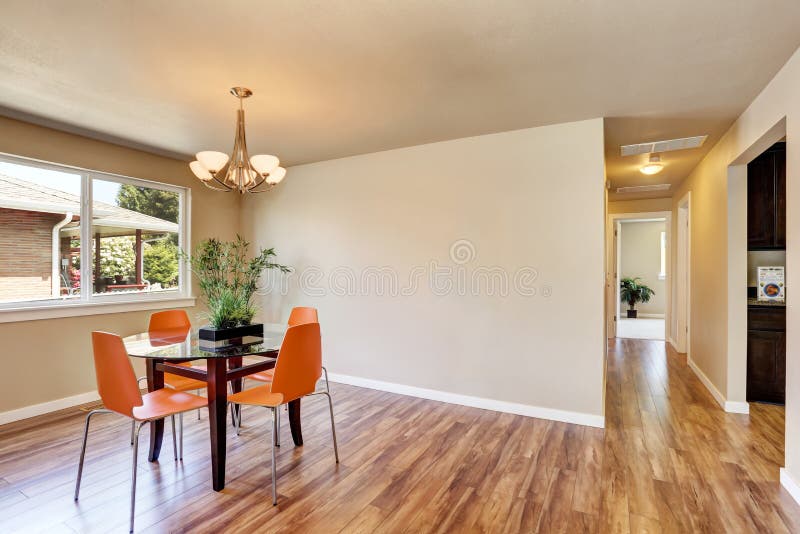 Modern Dining Area with Orange Chairs and Glass Table. Stock Photo